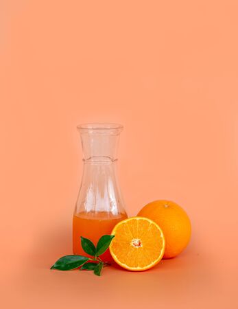 Orange juice in the glass jar with fresh orange on orange color background.の写真素材