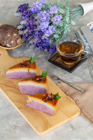 piece of taro chiffon cake topped with Thai taro custard and fried onion on wooden board with tea,...