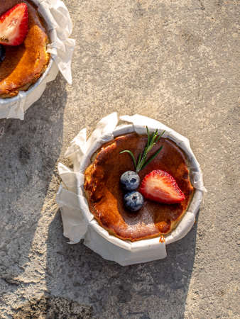 Burnt Cheese Cake, Basque Cheesecake with strawberry and blueberry toppings on Parchment Paper. top view.の写真素材
