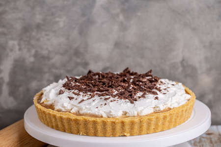 Homemade Banoffee pie with caramel, banana and chocolate topping on white cake stand.の写真素材