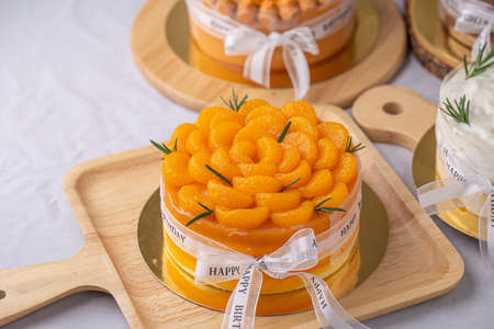 Fresh orange cake soft fudge decorated with orange pulp for birthday cake on wooden board.の写真素材