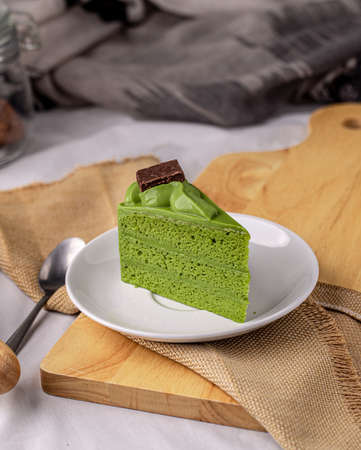 Japanese matcha green tea cake topping with chocolate past on white plate.の写真素材