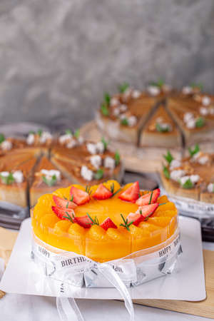Fresh orange cake soft fudge decorated with orange pulp and strawberry for birthday cake on wooden board.の写真素材