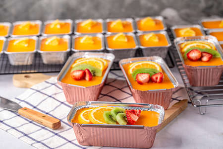 Fresh orange cake topping with orange pulp kiwi fruit and strawberry in foil cup.の写真素材