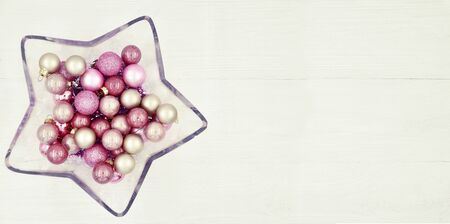 Star shaped glass vase with Christmas balls on a wooden white background.の写真素材