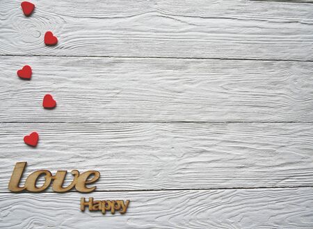 Small red hearts and decorative wooden words on a white desk. Valentines Day background.の写真素材