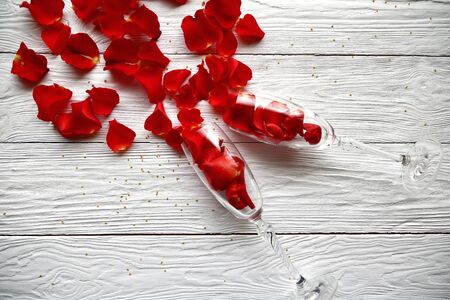 Red rose petals spilled out of wine glasses. Valentines Day background.の写真素材