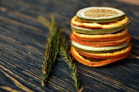A stack of dried slices of orange and lime on a dark wooden background. Side view.の写真素材