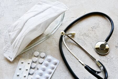 Medical mask, pill packs and stethoscope on a stone background. Top view.の写真素材