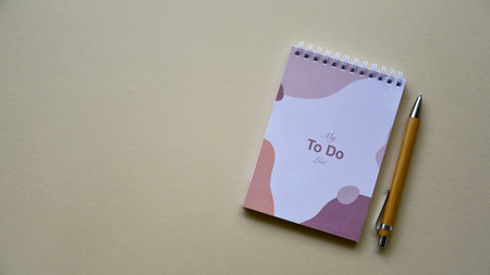 Notepad with wooden pen on a beige paper background. Top view. Close-up. Flat lay.