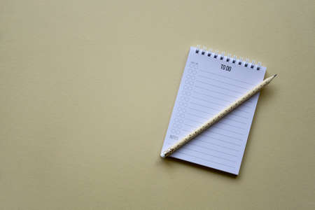Notepad with pencil on a beige paper background. Top view. Close-up. Flat lay.の写真素材