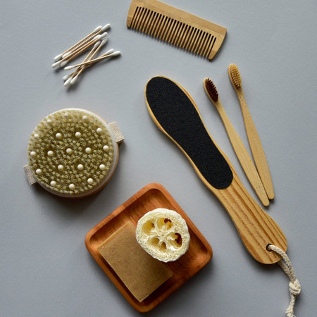 Bamboo toothbrushes, natural soap and bath loofah on a wooden plate, wooden dry massage brush and...