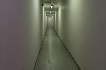 Long, tight and empty hallway on an eye-level angle with yellow-greenish light
