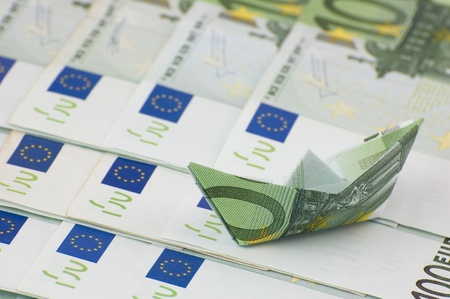 Paper ship made of euro banknote sailing on moneyの写真素材