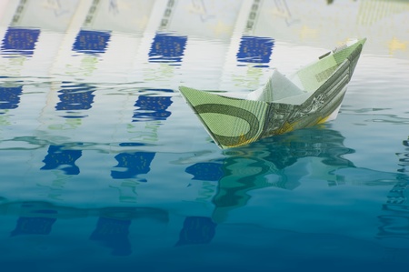 Paper ship made of euro banknote sailing on moneyの写真素材