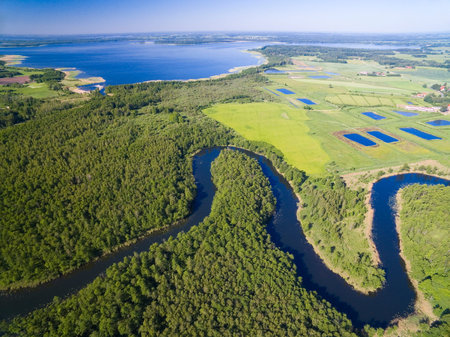 Meander of Wegorapa river flowing across wetlands, Mazury, Poland. Mamry Lake in the background