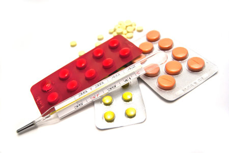 Pills and thermometer on white background