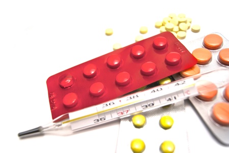 Pills, and thermometer close-up on white backgroundの写真素材