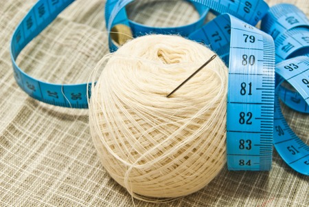 white yarn with needle and meter on fabric closeupの写真素材