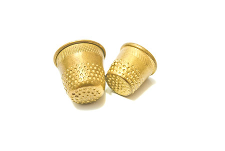 two metal golden thimbles on white background