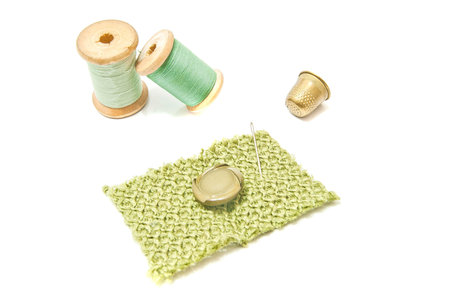 spools of thread, button and thimble on white
