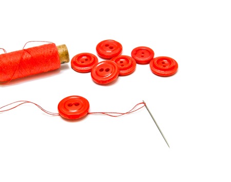 spool of red thread and buttons on white backgroundの写真素材