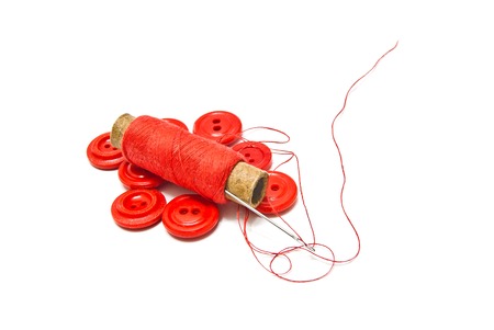 spool of thread and red buttons on white backgroundの写真素材