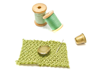 spools of thread, button and thimble on white background