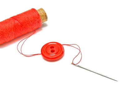 spool of red thread, button and needle on whiteの写真素材