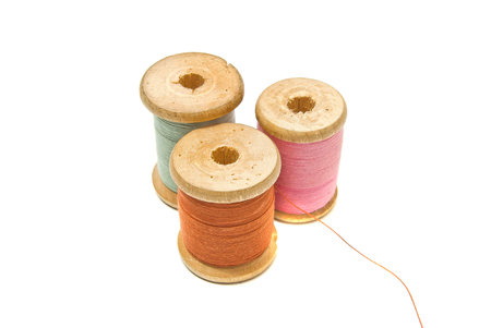 three spools of different thread on white