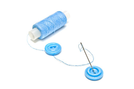 spool of blue thread and buttons on white background