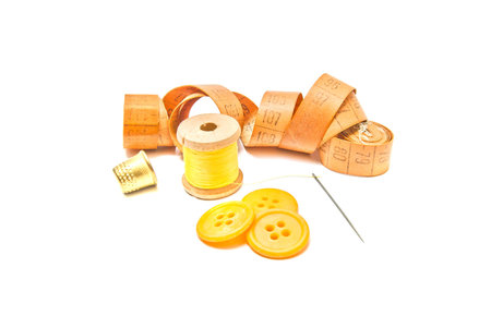 thimble, buttons and spool of thread on white