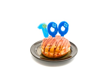 donut with one hundred years birthday candle on whiteの写真素材