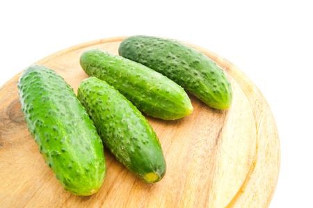 four cucumbers on cutting board on whiteの写真素材