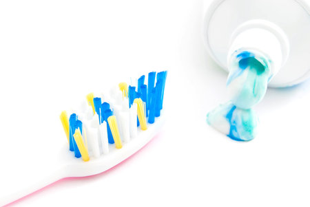 toothbrush and tube of toothpaste on white