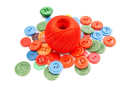 ball of thread and colored buttons on white background