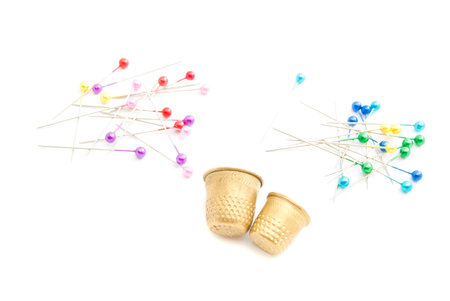 colored pins and thimbles on white background closeup