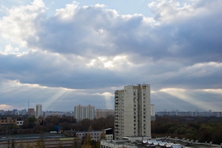sunbeams breaking through the massive clouds in cityの写真素材