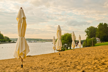 umbrellas on the beach next to a pond at sunsetの写真素材