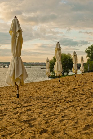 umbrellas on the beach next to pond at sunsetの写真素材