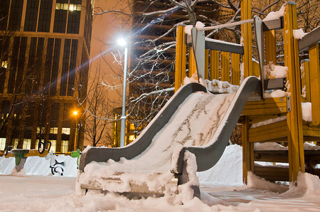 children's slide in the snow in the winter eveningの写真素材