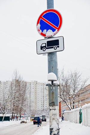road signs under the snow near the road and buildingsの写真素材