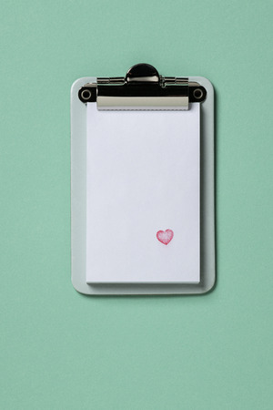 Clipboard on turquoise background. Flat lay, top view trendy for banner with heartの写真素材