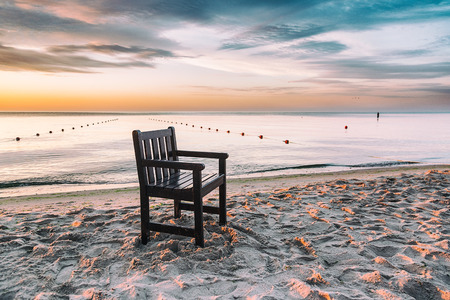 Chair left on the beach at sunriseの写真素材