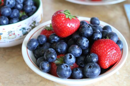 Plate with strawberries and blueberries on the tableの写真素材