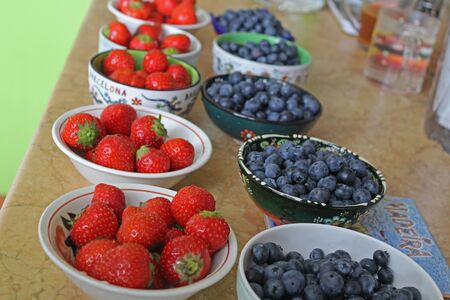 Plates with strawberries and blueberries on the tableの写真素材