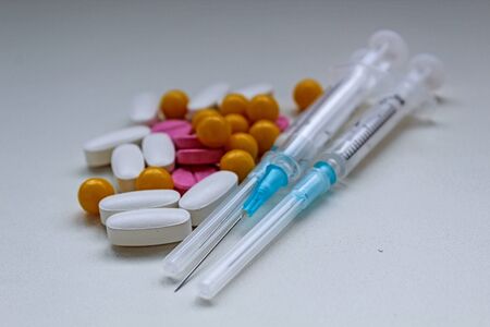 White, yellow and rose tablets pills and three syringes on white backgroundの写真素材
