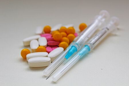 White, yellow and rose tablets pills and three syringes on white backgroundの写真素材