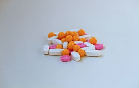 White, yellow and rose tablets pills on white backgroundの写真素材