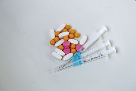 White, yellow and rose tablets pills and three syringes on the tableの写真素材